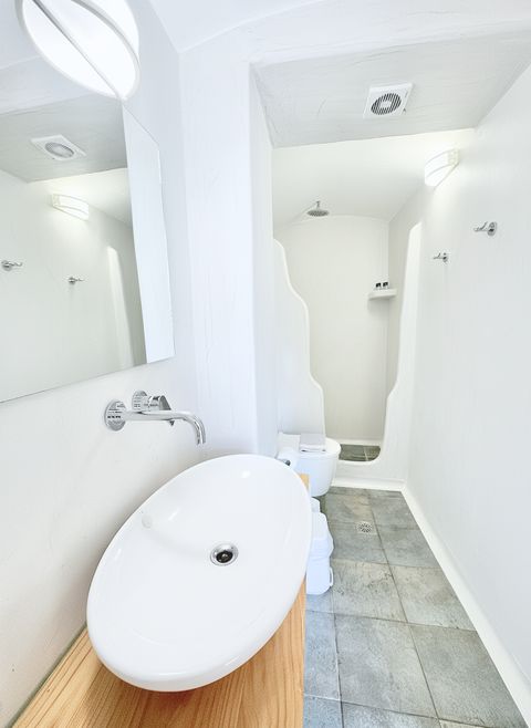 Bathroom with oval basin on a wooden counter and walk-in shower behind