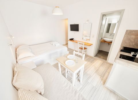Double bed, cushioned daybed, dining table, desk and kitchenette in one bright room