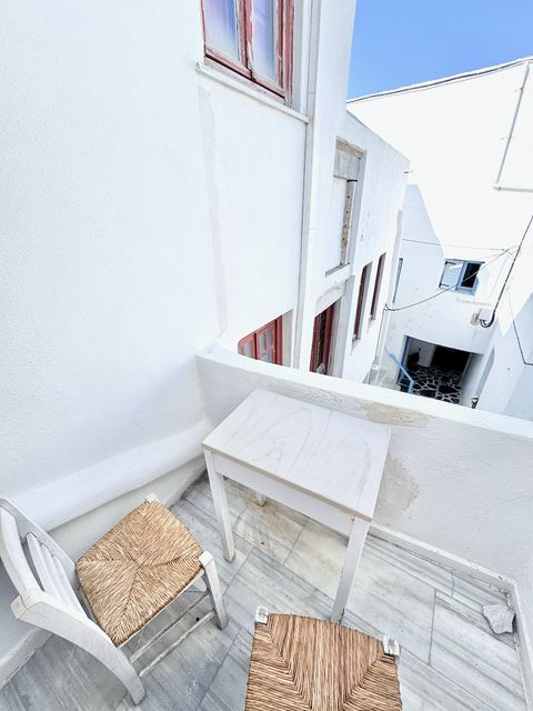 Private balcony with table and rush-seat chairs overlooking whitewashed Chora houses