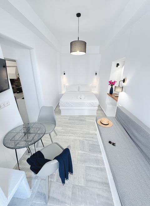 Double bed under a pendant lamp, with long built-in sofa and glass bistro table