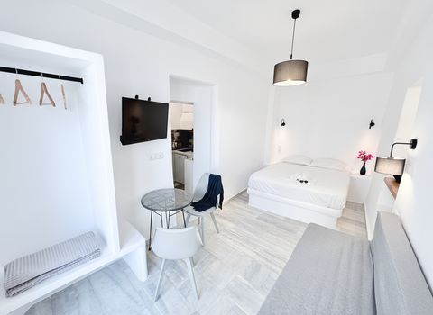 Open hanging rail, wall-mounted TV and bistro table, with the double bed beyond